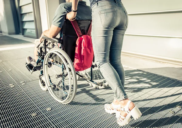 Закрыть глаза на женщину, толкающую инвалидное кресло со своим парнем — стоковое фото