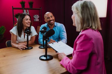 Üç farklı birey, bir ev sahibi ve birkaç konuk, bir ses podcast 'i kaydederken gülümsüyor ve sohbete dalıyorlar ya da profesyonel bir stüdyoda mikrofonla canlı yayın yapıyorlar.