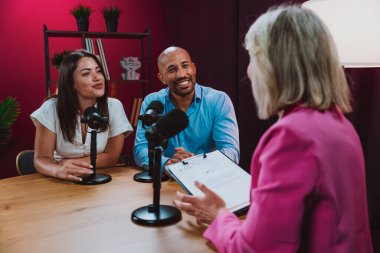 Üç farklı birey, bir ev sahibi ve birkaç konuk, bir ses podcast 'i kaydederken gülümsüyor ve sohbete dalıyorlar ya da profesyonel bir stüdyoda mikrofonla canlı yayın yapıyorlar.