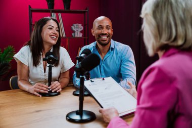 Üç farklı birey, bir ev sahibi ve birkaç konuk, bir ses podcast 'i kaydederken gülümsüyor ve sohbete dalıyorlar ya da profesyonel bir stüdyoda mikrofonla canlı yayın yapıyorlar.