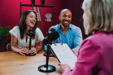 Üç farklı birey, bir ev sahibi ve birkaç konuk, bir ses podcast 'i kaydederken gülümsüyor ve sohbete dalıyorlar ya da profesyonel bir stüdyoda mikrofonla canlı yayın yapıyorlar.