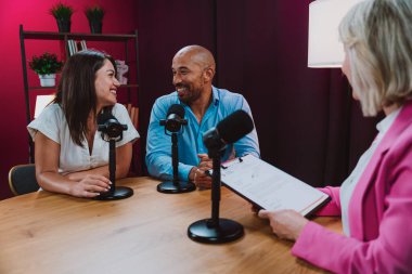 Üç farklı birey, bir ev sahibi ve birkaç konuk, bir ses podcast 'i kaydederken gülümsüyor ve sohbete dalıyorlar ya da profesyonel bir stüdyoda mikrofonla canlı yayın yapıyorlar.