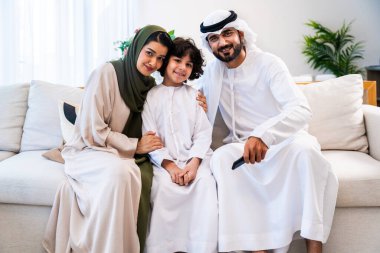 Geleneksel emirati kıyafetleri giyen Ortadoğu ailesi evde birlikte vakit geçiriyorlar. Emirati ailesi ev ortamında birlikte kaliteli zaman geçiriyor.