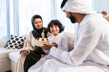 Geleneksel emirati kıyafetleri giyen Ortadoğu ailesi evde birlikte vakit geçiriyorlar. Emirati ailesi mutlu bir doğum günü kutlaması yapıyor.