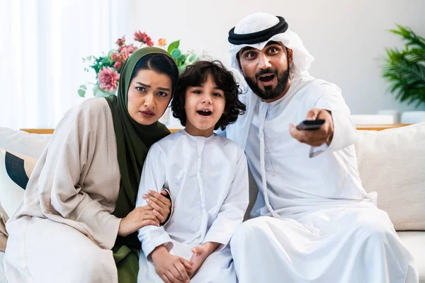 Geleneksel emirati kıyafetleri giyen Ortadoğu ailesi evde birlikte vakit geçiriyorlar. Emirati ailesi modern evlerinde birlikte televizyon izlerken şaşırdı.