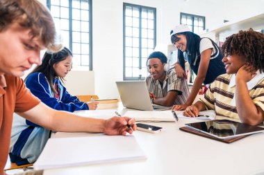 Kütüphanede buluşan çok ırklı bir grup genç öğrenci. Üniversite kütüphanesindeki bir masanın etrafında dizüstü bilgisayar ve kitaplarla işbirliği yapan ve çalışan bir grup genç öğrenci.