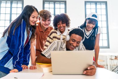 Kütüphanede buluşan çok ırklı bir grup genç öğrenci. Çalışma masasında işbirliği yapan ve öğrenen bir grup genç. Bir dizüstü bilgisayarı paylaşıyorlar ve modern bir kütüphanede gülümsüyorlar.