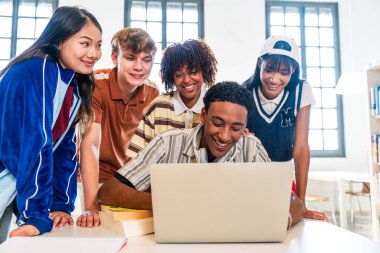 Kütüphanede buluşan çok ırklı bir grup genç öğrenci. Okul projesinde işbirliği yaparken gülümseyen, modern bir kütüphanede dizüstü bilgisayardan içeriği izleyen çok ırklı genç insanlar.