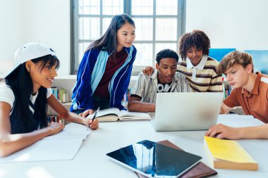 Kütüphanede buluşan çok ırklı bir grup genç öğrenci. Modern bir kütüphanede bir dizüstü bilgisayarla bir proje üzerinde çalışan, çalışan ve araştırma yapan bir grup genç.