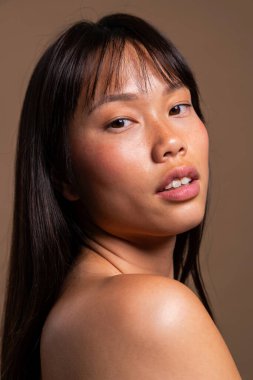 Renkli arka planda güzel bir Çinli kadın portresi. Genç Asyalı kadın omzunun üzerinden kameraya bakıyor, yeni parlayan ten, doğal güzellik ve stüdyo resminde kendine güvenen ifade.