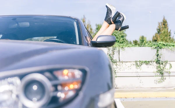 Girl with shoes out of the car window — стоковое фото