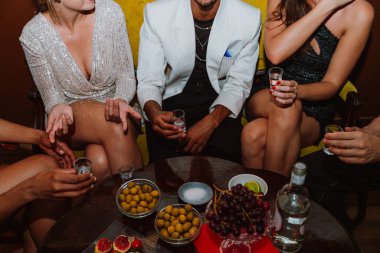 Çeşitli yetişkin arkadaş grupları sosyal bir toplantı sırasında kadehlerle tezahürat yapıyor, canlı bir barda ya da klüp ortamında aperatiflerle kutlama yapıyor ve eğleniyorlar.