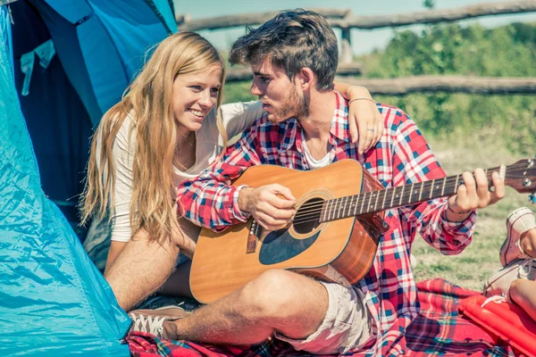 Couple play guitar in a campsite — Stock Photo, Image