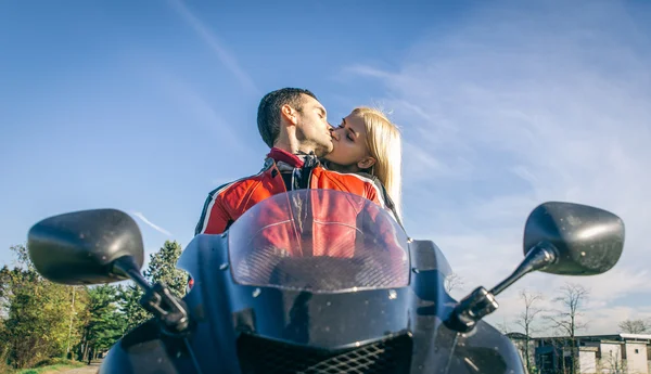 Счастливая молодая пара целуется на мотоцикле — стоковое фото