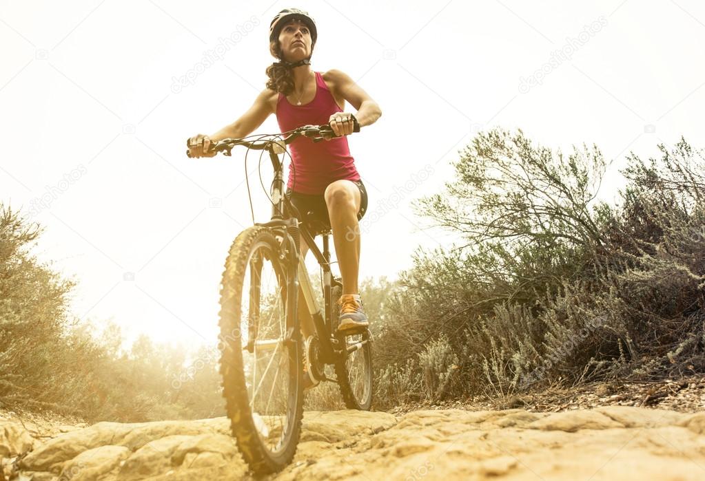 Young woman making downhill with her mountain bike
