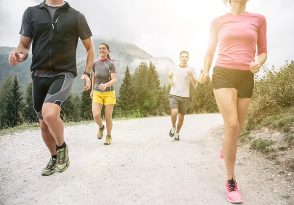 Cuatro amigos corriendo fuera de la carretera — Foto de Stock