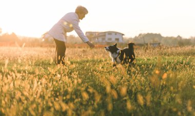 Orta yaş kadın onun kenar kömür ocağı köpekle oynamayı 