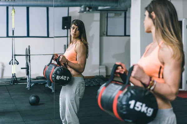 Mujer entrenamiento byceps muscular con levantamiento de bolsas pesadas —  Fotos de Stock