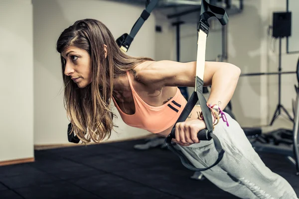 Mujer entrenando con elásticos en el gimnasio —  Fotos de Stock