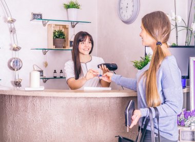 Kadın bir dükkanda kredi kartıyla ödeme yapar