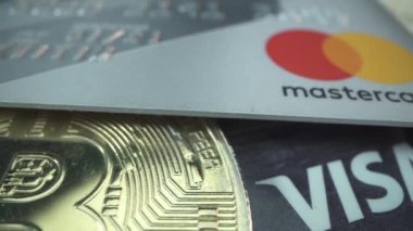 Stavropol, RUSSIA - 15 Ekim 2020: Süper makro görünüm altın bitcoin 'ler ve MasterCard Visa' nın banka kredi kartları birçok Amerikan doları ile dönüyor. Altın dijital kripto para ve
