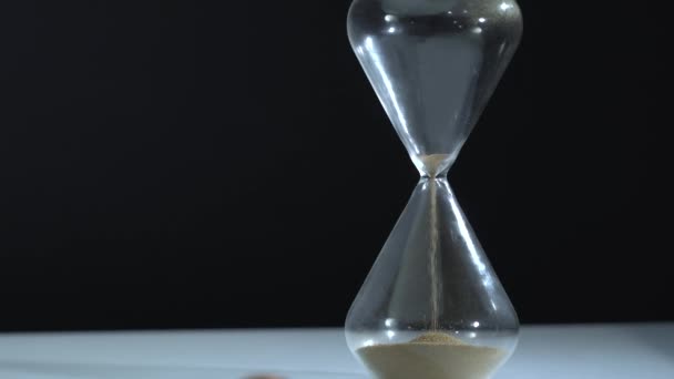 Hourglass and gold Bitcoin in frame. Sand finish fall to the bottom and focus shift to digital crypto coin. Time is money concept. Dark background. Blockchain technology. — Stock Video