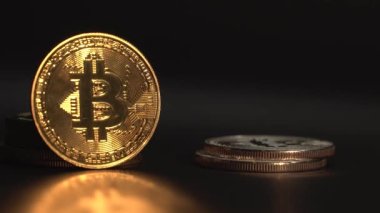 Altın kripto para birimi Bitcoin siyah yüzeyde yansımayla döner. İnsanlar yüzeye başka bir kripto para koydular. Karanlık arka plan. Engelleme teknolojisi. Madencilik ve ticaret kavramı