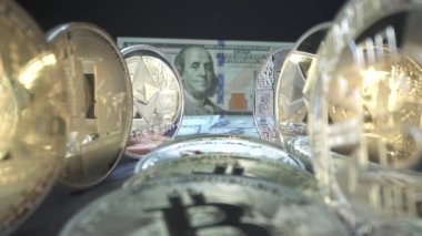 Altın kripto sikkeleri Bitcoin, Etherium, Zcash yüzeydeki yansıma ile aynı hizada masanın üzerinde. Arka planda Benjamin Franklin resmi olan 100 dolarlık banknot. Finans konsepti. Engelleme zinciri