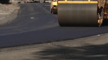 Yol tamiri. Asfalt döşeme. Tekerlek yeni bırakılmış asfaltı düzleştiriyor. Yolda yeni bir asfalt yuvarlayan tekerlekli sanayi arazisi. Tamir et. Paten kaymanın büyük çalışma makinesi.