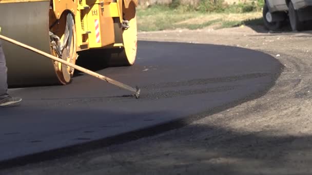 Reparación. Puesta de asfalto. Los trabajadores nivelan la superficie de la carretera recién colocada y el rodillo hace la compactación final. Industria. Equipo especial de carretera, trabajo — Vídeos de Stock