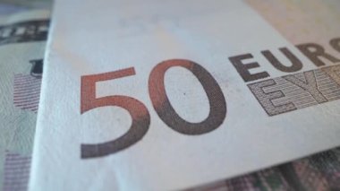 Yakından bakıldığında, beyaz masa arkasında izole edilmiş Avro banknotlarının birkaç banknotunun videosu görülüyor. Avro parasının banknotu. Finans ve iş konsepti