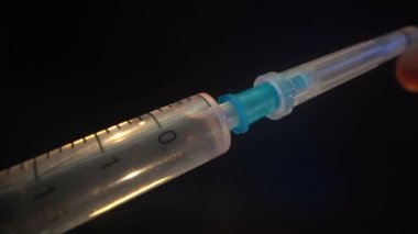 İğnenin kapağı kapalı olan tek kullanımlık yeni bir şırınganın yakın çekimi. Doktor, ilacı hastaya vermeden önce iğnenin kapağını çıkartıyor. Virüs için verilen ilaç...