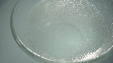 Fışkırtıcı ilaçlar. Tablet çözülüyor. Beyaz yuvarlak tabletler kabarcıklarla suya düşer. Beyaz arka plan. Covid küresel salgın konsepti.