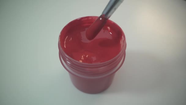 Close up of hand painter mixing paint in plastic paint can with wooden stick. Close up. Red paint. Draw the pucture. White surface. Rotating paint and tassel. — Stock Video