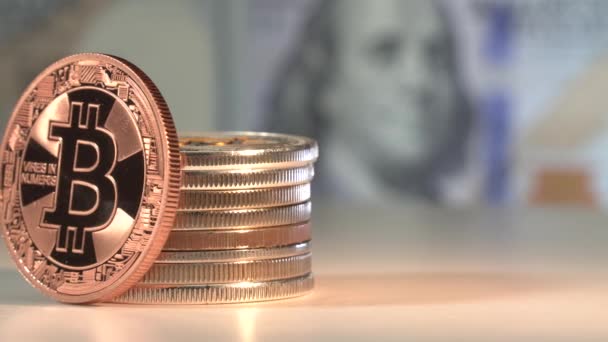 Zlatá mince Bitcoin otáčet na odraženém povrchu s mnoha dalšími kryptocoiny. Americký dolar na pozadí s Benjaminem Franklinem na bankovce za 100 dolarů. Koncept Blockchain. Pupulární kryptoměna — Stock video