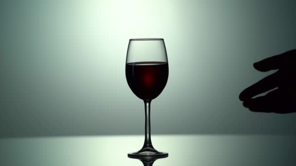 Mans silueti teslim etti ve bir bardak şarap aldı. Kırmızı şarap şişeden cama doğru akıyor. Görüntü izole edilmiş. El ele tutuşan şişe. Yavaş çekim — Stok video