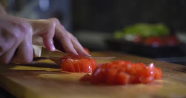 Chica blanca está preparando ensalada en la cocina por la noche. Corta verduras. Comida saludable Hermosos tomates rojos maduros cultivados en un invernadero, gotas de agua macro video. Hortalizas orgánicas crudas — Vídeos de Stock