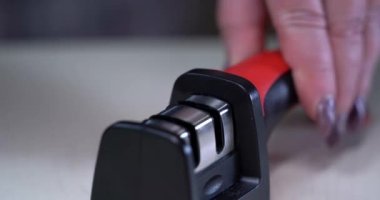 Bir adam bileytaşını yakın plan çekimle keskinleştirir. Şef bıçakları yavaş çekimde biler. Mutfak restoranında yemek pişirmeye hazır olun. Erkek profesyonel keskinleştirmeye yakın durun.