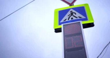 Yaya trafiği ışıklarına yakın çekim. İki trafik ışığı kırmızıya döner ve yeşile döner. Geri sayım saniyeleri. Şehir hayatı gerçek zamanlı. Gündüz vakti şehir sokakları. Sokakta kırmızı ışıktan kırmızı ışığa kadar kamera var.