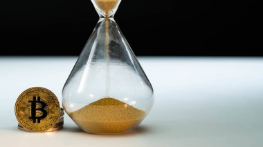 Siyah arka planlı beyaz masada altın Bitcoin ve kum saati. Makro atış. Vakit nakittir, Etherium, Litecoin, Ripple, Xrp, Dogecoin, Defi
