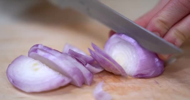 Vista de cerca de las manos de una mujer cortar cebolla roja en rodajas con un cuchillo. Anillo de cebolla roja. Preparando comida. Cortar la cebolla. Proceso de cocción. — Vídeos de Stock