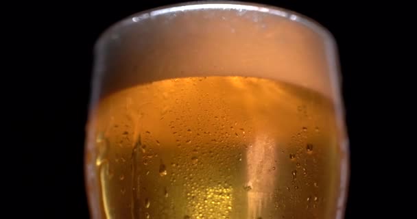 Χαμηλή γωνία αφρώδους μπύρας γεμίζοντας γυάλινο κύπελλο σε αργή κίνηση σε μαύρο φόντο. Ελαφριά μπύρα σε ποτήρι. Με φυσαλίδες και αφρό. — Αρχείο Βίντεο