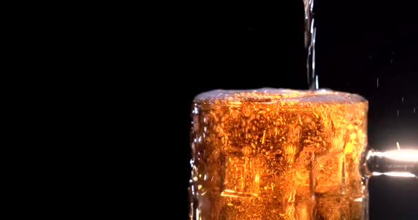 黒の背景に冷たいビールのガラスカップから上昇し、こぼれる柔らかい白い泡の低い角度。パブのコンセプト。ハードウィークの後 — ストック動画
