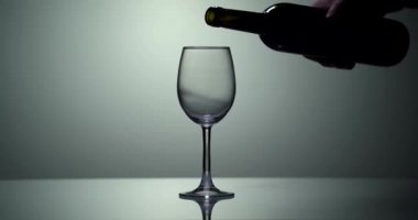 Şarap kadehini süper yavaş çekimde beyaz şarapla doldurun. Mavi arka planda kadehe altın şarap dökülüyor. Beyaz şarap, cam içinde güzel bir dalga oluşturur. Yaratıcı makro yavaş