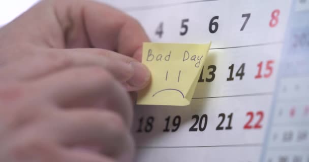 The hand sticks a reminder on the calendar about bad day. — Stock Video