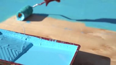 Bir adam eski bir ahşap tahtayı boyuyor. Kamera perspektifinden çekilmiş. Bakış açısı. Fırçayı kahverengi bir kutuya daldır. Tahtanın parçalarını yavaş çekimde boyuyor. Yenileme, Ev İşi, Restorasyon