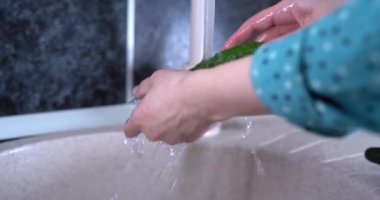 Kadınların elleri su altında salatalık yıkar, yakın çekim, seçici çekim. Kadınların elleri musluğun altında salatalığı suyla yıkıyor. Yemeden önce meyve yıkıyorum. 4k video