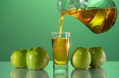 Beyaz arka plana taze elma suyu döküyorum. Yeşil arka plan. Yaz havası. Çiğ fotoğraf