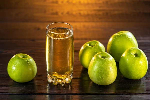 Un vaso de jugo de manzana con manzanas verdes en el fondo del atardecer. Bonita mesa de madera. Día de verano. Buen humor.. — Foto de Stock