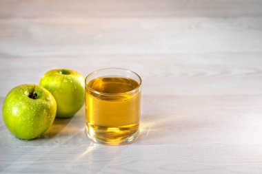 Gün batımında yeşil elmalı bir bardak elma suyu. Güzel beyaz ahşap masa. Yaz günü. Keyfin yerinde..